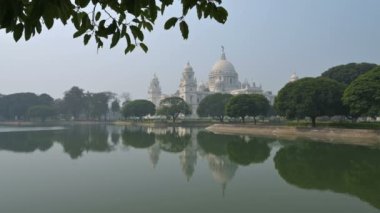 Kolkata 'daki büyük mermer bina Victoria Memorial' ın 4K stok videosu, Kolkata 'nın ünlü anıtı, Batı Bengal, Hindistan. Binanın tepesinin ön plandaki göl suyunun yansıması..