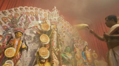 Kolkata, Hindistan -13 Ekim 2021: Hindu rahibi tanrıça Durga 'ya ghanta ve chamor ile tapıyor. Ashtami puja aarati - kutsal Durga Puja ritüeli - gece çekildi. 4K video.