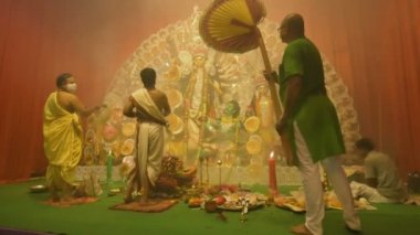 Kolkata, Hindistan - 13 Ekim 2021: Hindu rahipler Tanrıça Durga 'ya deniz kabuğu kabuğu veya shankha, chamor ve el vantilatörü ile tapıyorlar. Ashtami puja aarati - kutsal Durga Puja ritüeli - gece çekildi. 4K video.