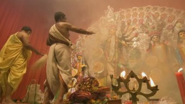 Kolkata, Hindistan -13 Ekim 2021: Hindu rahipler Tanrıça Durga 'ya panchpradip, kutsal lamba ve chamor ile tapıyorlar. Ashtami puja aarati - kutsal Durga Puja ritüeli - ön planda panchapradip yaktı.