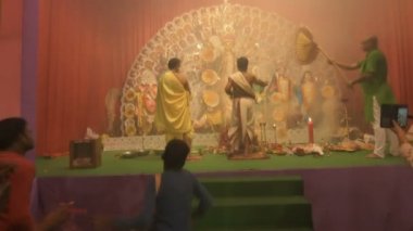Kolkata, Hindistan -13 Ekim 2021: Dhaakis dhaaks oynarken Hindu rahipler kabuklu veya shankha, chamor ve el vantilatörü ile tanrıça Durga 'ya tapıyorlar. Ashtami puja aarati - kutsal Durga Puja ritüeli.