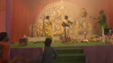 Kolkata, Hindistan -13 Ekim 2021: Dhaakis dhaaks oynarken Hindu rahipler kabuklu veya shankha, chamor ve el vantilatörü ile tanrıça Durga 'ya tapıyorlar. Ashtami puja aarati - kutsal Durga Puja ritüeli.