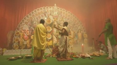Kolkata, Hindistan -13 Ekim 2021: Hindu rahipler ayna, chamor ve el vantilatörü ile tanrıça Durga 'ya tapıyorlar. Ashtami puja aarati - kutsal Durga Puja ritüeli - gece çekildi. 4K video.