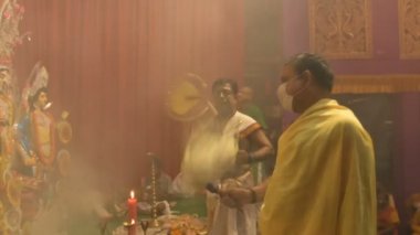 Kolkata, Hindistan - 13 Ekim 2021: Hindu rahipler tanrıça Durga 'ya Shaari ile tapıyorlar, Hint kadın elbisesi, chamor ve el fanı. Ashtami puja aarati - kutsal Durga Puja ritüeli - gece çekildi.