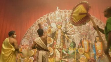 Kolkata, Hindistan - 13 Ekim 2021: Hindu rahipler tanrıça Durga 'ya Shaari ile tapıyorlar, Hint kadın elbisesi, chamor ve el fanı. Ashtami puja aarati - kutsal Durga Puja ritüeli - gece çekildi.