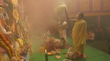 Kolkata, Hindistan - 13 Ekim 2021: Hindu rahipler tanrıça Durga 'ya Shaari ile tapıyorlar, Hint kadın elbisesi, chamor ve el fanı. Ashtami puja aarati - kutsal Durga Puja ritüeli - gece çekildi.