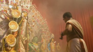 Kolkata, Hindistan -13 Ekim 2021: Hindu rahibi tanrıça Durga 'ya ghanta ve chamor ile tapıyor. Ashtami puja aarati - kutsal Durga Puja ritüeli - gece çekildi. 4K video.