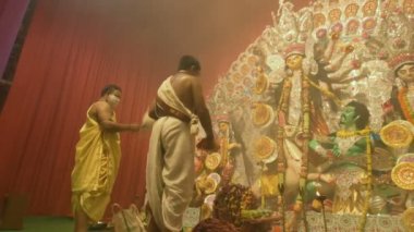 Kolkata, Hindistan -13 Ekim 2021: Hindu rahipleri Tanrıça Durga 'ya Shaari, chamor ve el fanı ile tapıyorlar. Ashtami puja aarati - kutsal Durga Puja ritüeli - gece çekildi. 4K video.