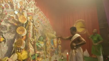 Kolkata, Hindistan -13 Ekim 2021: Hindu rahipler tanrıça Durga 'ya ghanta, chamor ve el yelpazesiyle tapıyorlar. Ashtami puja aarati - kutsal Durga Puja ritüeli - gece çekildi. 4K video.