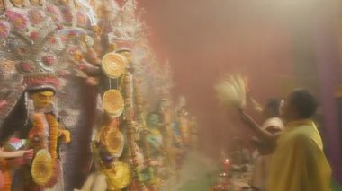 Kolkata, Hindistan - 13 Ekim 2021: Hindu rahipler tanrıça Durga 'ya Shaari ile tapıyorlar, Hint kadın elbisesi, chamor ve el fanı. Ashtami puja aarati - kutsal Durga Puja ritüeli - gece çekildi.
