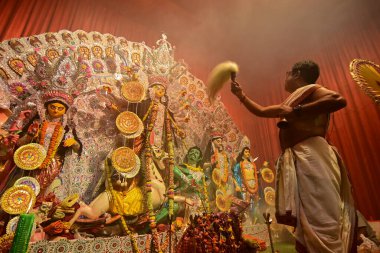 Howrah, Hindistan -13 Ekim 2021: Hindu Rahipler Tanrıça Durga 'ya Ganta, chamor ve el yelpazesiyle tapıyorlar. Ashtami puja aarati - kutsal Durga Puja ritüeli - gece çekildi.