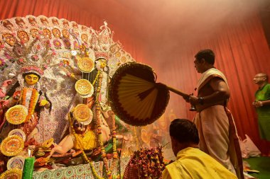 Howrah, Hindistan -13 Ekim 2021: Hindu rahip tanrıça Durga 'ya ghanta ve el yelpazesiyle tapıyor. Ashtami puja aarati - kutsal Durga Puja ritüeli - gece çekildi.