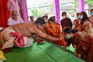 Howrah, Batı Bengal, Hindistan - 14 Ekim 2021: Hindu Purohit, Tanrıça Durga 'ya ibadet etmek için tanrıça Durga' ya itme sırasında dindarların alınlarına kutsal tilak takıyor..