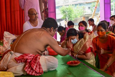 Howrah, Batı Bengal, Hindistan - 14 Ekim 2021: Hindu Purohit, Tanrıça Durga 'ya ibadet etmek için tanrıça Durga' ya itme sırasında dindarların alınlarına kutsal tilak takıyor..