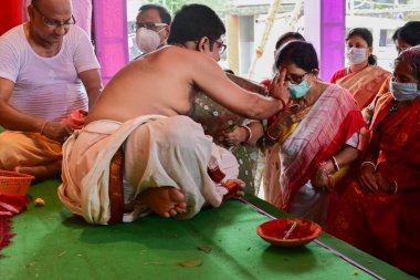 Howrah, Batı Bengal, Hindistan - 14 Ekim 2021: Hindu Purohit, Tanrıça Durga 'ya ibadet etmek için tanrıça Durga' ya itme sırasında dindarların alınlarına kutsal tilak takıyor..
