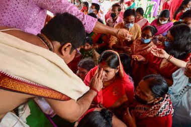 Howrah, Batı Bengal, Hindistan - 14 Ekim 2021: Hindu Purohit, Tanrıça Durga 'ya ibadet etmek için tanrıça Durga' ya itme sırasında dindarların alınlarına kutsal tilak takıyor..