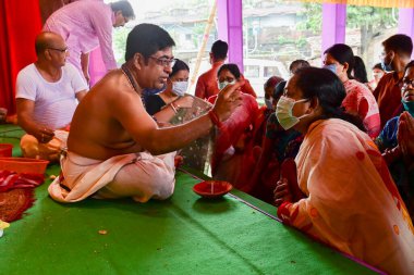 Howrah, Batı Bengal, Hindistan - 14 Ekim 2021: Hindu Purohit, Tanrıça Durga 'ya ibadet etmek için tanrıça Durga' ya itme sırasında dindarların alınlarına kutsal tilak takıyor..