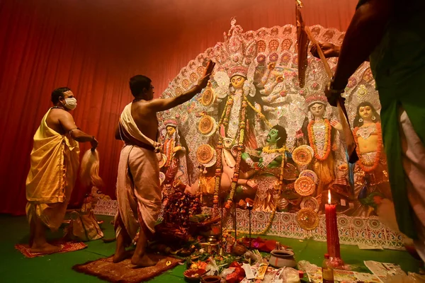 Howrah, Hindistan -13 Ekim 2021: Hindu Rahipler Tanrıça Durga 'ya Shari, ghanta, chamor ve el fanı ile tapıyorlar. Ashtami puja aarati - kutsal Durga Puja ritüeli - gece çekildi.