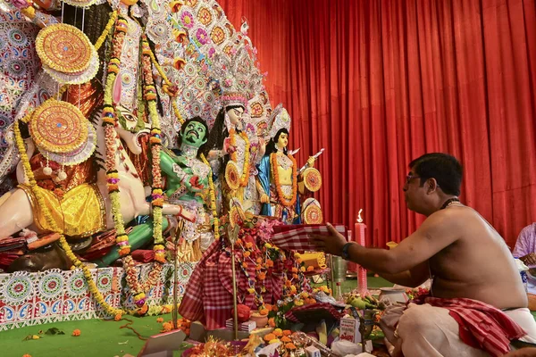 Howrah, Batı Bengal, Hindistan - 14 Ekim 2021: Hindu Purohit Sanskrit shlokas 'ın tanrıça Durga' ya itme hareketi, tanrıçaya çiçeklerle tapınma ritüeli.