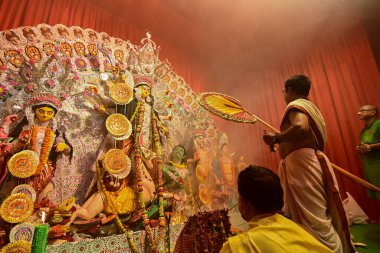 Howrah, Hindistan -13 Ekim 2021: Hindu rahip tanrıça Durga 'ya ghanta ve el yelpazesiyle tapıyor. Ashtami puja aarati - kutsal Durga Puja ritüeli - gece çekildi.