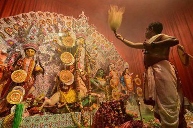 Howrah, Hindistan -13 Ekim 2021: Hindu Rahipler Tanrıça Durga 'ya Ganta, chamor ve el yelpazesiyle tapıyorlar. Ashtami puja aarati - kutsal Durga Puja ritüeli - gece çekildi.
