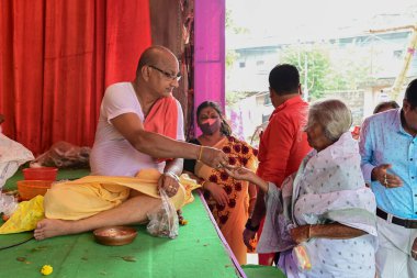 Howrah, Batı Bengal, Hindistan - 14 Ekim 2021: Hindu Purohit Charanomrito, kutsal su ve çiçeği tanrıça Durga 'ya ibadet etmek için tanrıça Durga' ya adadı..