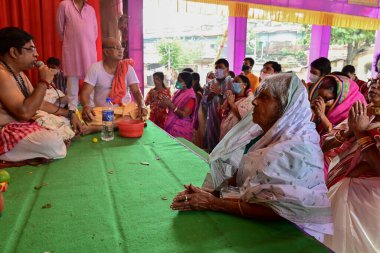 Howrah, Batı Bengal, Hindistan - 14 Ekim 2021: Yaşlı Bengalli dul tanrıça Durga 'ya taparken Hindu Purohit Hindu dindarlar için Sanskritçe shlokas söylerken tanrıçaya pejali sundu.