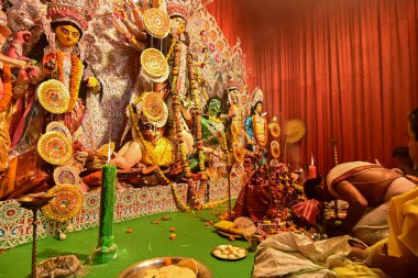 Howrah, Hindistan -13 Ekim 2021: Hindu rahip tanrıça Durga 'ya ghanta, chamor ve el vantilatörü ile ibadet ederken dua ediyor. Ashtami puja aarati - kutsal Durga Puja ritüeli - gece çekildi.