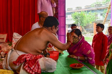 Howrah, Batı Bengal, Hindistan - 14 Ekim 2021: Hindu Purohit, Tanrıça Durga 'ya ibadet etmek için tanrıça Durga' ya itme sırasında dindarların alınlarına kutsal tilak takıyor..