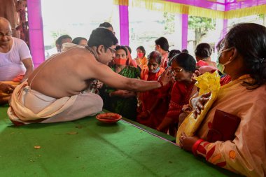 Howrah, Batı Bengal, Hindistan - 14 Ekim 2021: Hindu Purohit, Tanrıça Durga 'ya ibadet etmek için tanrıça Durga' ya itme sırasında dindarların alınlarına kutsal tilak takıyor..
