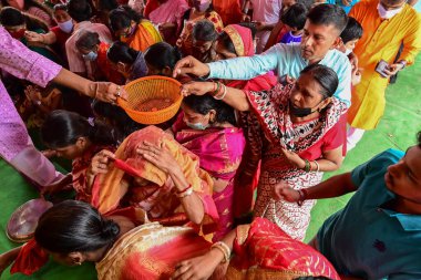 Howrah, Batı Bengal, Hindistan - 14 Ekim 2021: Hindu dindarlar Tanrıça Durga 'ya kakalamak için sepetin içine para koyuyorlar, tanrıçaya çiçeklerle ve zenginlik için parayla ibadet etme ritüeli..