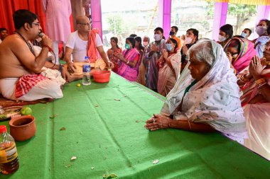 Howrah, Batı Bengal, Hindistan - 14 Ekim 2021: Yaşlı Bengalli dul tanrıça Durga 'ya taparken Hindu Purohit Hindu dindarlar için Sanskritçe shlokas söylerken tanrıçaya pejali sundu.