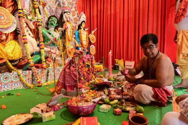 Howrah, Batı Bengal, Hindistan - 14 Ekim 2021: Hindu Purohit Sanskrit shlokas 'ın tanrıça Durga' ya itme hareketi, tanrıçaya çiçeklerle tapınma ritüeli.