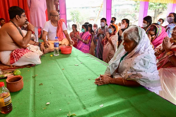 Howrah, Batı Bengal, Hindistan - 14 Ekim 2021: Yaşlı Bengalli dul tanrıça Durga 'ya taparken Hindu Purohit Hindu dindarlar için Sanskritçe shlokas söylerken tanrıçaya pejali sundu.