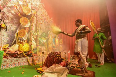 Howrah, Hindistan -13 Ekim 2021: Hindu Rahipler Tanrıça Durga 'ya Ganta, chamor ve el yelpazesiyle tapıyorlar. Ashtami puja aarati - kutsal Durga Puja ritüeli - gece çekildi.
