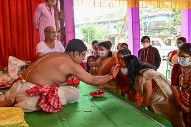 Howrah, Batı Bengal, Hindistan - 14 Ekim 2021: Hindu Purohit, Tanrıça Durga 'ya ibadet etmek için tanrıça Durga' ya itme sırasında dindarların alınlarına kutsal tilak takıyor..
