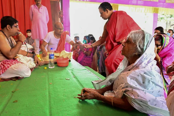 Howrah, Batı Bengal, Hindistan - 14 Ekim 2021: Yaşlı Bengalli dul tanrıça Durga 'ya taparken Hindu Purohit Hindu dindarlar için Sanskritçe shlokas söylerken tanrıçaya pejali sundu.