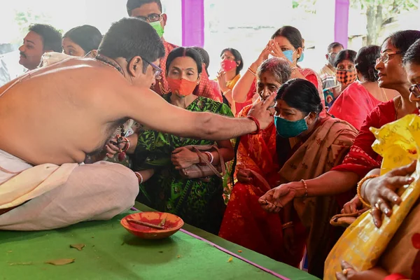 Howrah, Batı Bengal, Hindistan - 14 Ekim 2021: Hindu Purohit, Tanrıça Durga 'ya ibadet etmek için tanrıça Durga' ya itme sırasında dindarların alınlarına kutsal tilak takıyor..