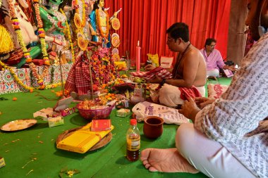 Howrah, West Bengal, India - 14th October 2021 : Hindu Purohit uttering Sanskrit shlokas offering pushpanjali to Goddess Durga, ritual to worship the Goddess with flowers.