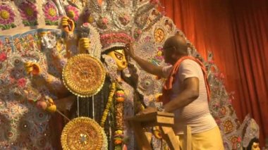 Howrah, India - October 15th, 2021 : Hindu priest putting vermilion, sindoor on Goddess Durga's forehead before Sandhi Puja, the sacred juncture of Ashtami and Nabami, as Hindu ritual for praying.