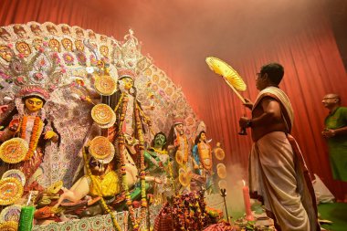 Howrah, Hindistan -13 Ekim 2021: Hindu Rahipler Tanrıça Durga 'ya Ganta, chamor ve el yelpazesiyle tapıyorlar. Ashtami puja aarati - kutsal Durga Puja ritüeli - gece çekildi.