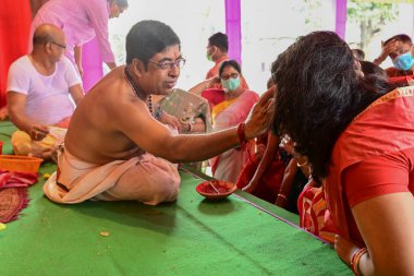 Howrah, Batı Bengal, Hindistan - 14 Ekim 2021: Hindu Purohit, Tanrıça Durga 'ya ibadet etmek için tanrıça Durga' ya itme sırasında dindarların alınlarına kutsal tilak takıyor..