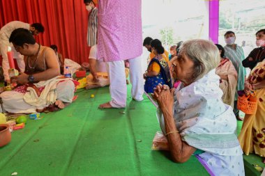 Howrah, West Bengal, India - 14th October 2021 : Senior aged Bengali widow worshipping Goddess Durga during pushpanjali to Goddess Durga, Ashtami puja of Durga Puja festival.