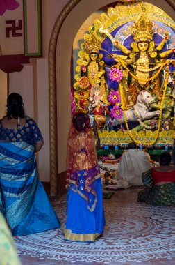 Howrah,India -October 26th,2020 : Bengali girl child taking picture of Goddess Durga inside old age decorated home. Durga Puja, biggest festival of Hinduism, UNESCO cultural heritage of humanity.