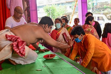 Howrah, Batı Bengal, Hindistan - 14 Ekim 2021: Hindu Purohit, Tanrıça Durga 'ya ibadet etmek için tanrıça Durga' ya itme sırasında dindarların alınlarına kutsal tilak takıyor..
