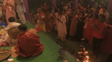 Howrah, India- October 15th, 2021 : Hindu devotees praying to Goddess Durga with folded hands on Sandhi Puja, the sacred juncture of Ashtami and Nabami, as ritual. Holy 18 lamps are lit.