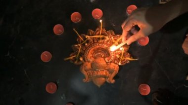 Indian woman lighting up diwali candles or diya put in circle. Deepawali lights at night. Dark background stock footage.