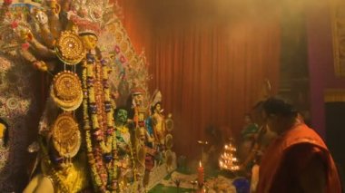 Howrah, India- October 15th, 2021 : Hindu purohits worshipping Goddess Durga with holy lamps and chamor on Sandhi Puja, the sacred juncture of Ashtami, eighth day and Nabami, nineth day, as ritual.