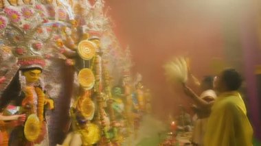 Kolkata, Hindistan - 13 Ekim 2021: Hindu rahipler tanrıça Durga 'ya Shaari ile tapıyorlar, Hint kadın elbisesi, chamor ve el fanı. Ashtami puja aarati - kutsal Durga Puja ritüeli - gece çekildi.