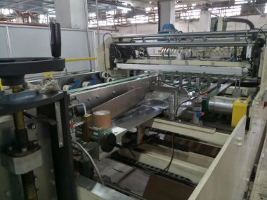 Kolkata, West Bengal, India - 16th May 2019 : Manufactured white Paper sheets are being slitted and rewinded in paper slitting and rewinding machine. in a paper manufacturing plant.